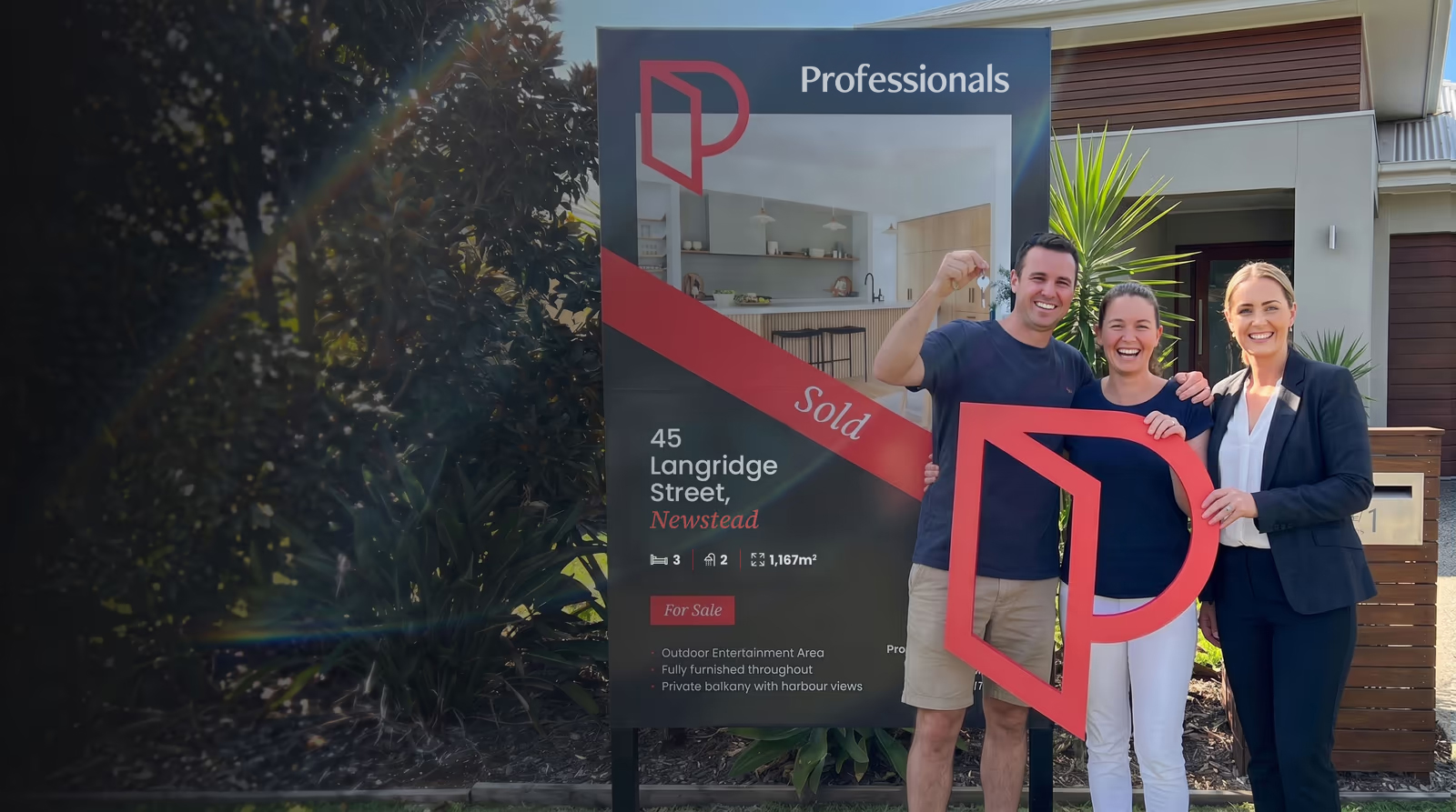 A couple and their Professionals agent celebrating a sold home, holding the Open Door P